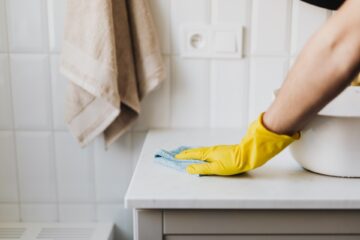 Cleaner with yellow rubber gloves, cleaning a counter top.